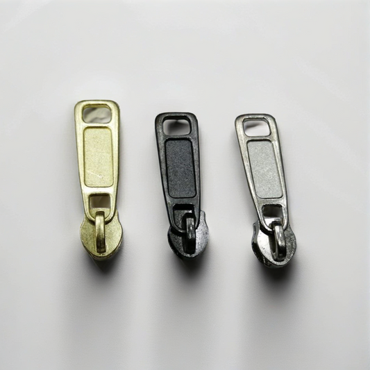 Three metal zipper pulls on a light gray background